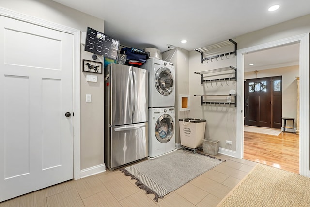 laundry room featuring baseboards, laundry area, stacked washing maching and dryer, and wood tiled floor