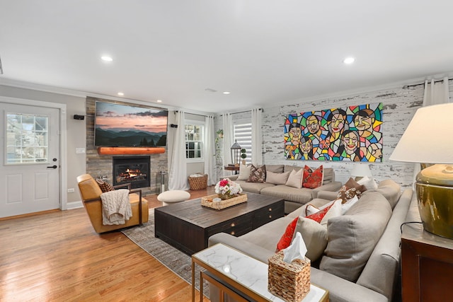 living area with baseboards, ornamental molding, a stone fireplace, light wood-type flooring, and recessed lighting