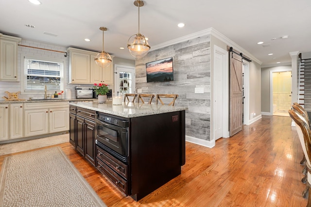 kitchen featuring light wood-type flooring, a sink, recessed lighting, and a barn door