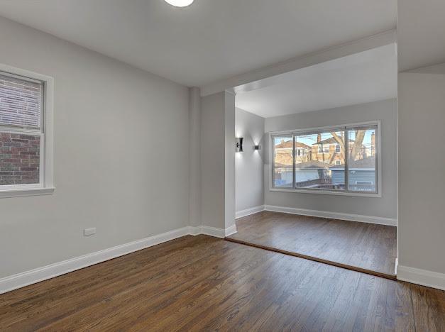 spare room featuring baseboards and wood finished floors