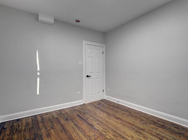 unfurnished room featuring dark wood-style flooring and baseboards