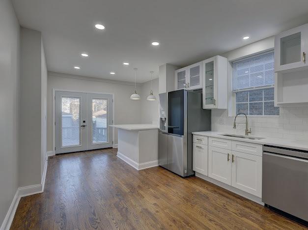 kitchen featuring french doors, dark wood finished floors, tasteful backsplash, appliances with stainless steel finishes, and a sink