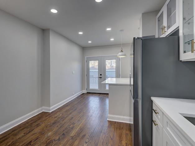 kitchen featuring dark wood finished floors, white cabinets, glass insert cabinets, freestanding refrigerator, and french doors