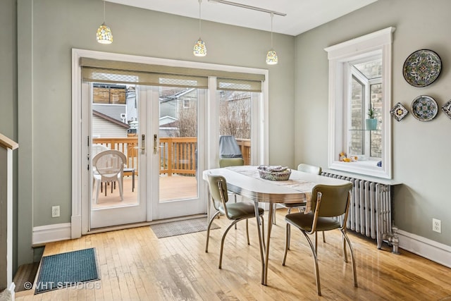 dining room with french doors, baseboards, radiator heating unit, and hardwood / wood-style flooring