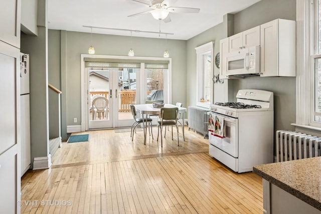 kitchen featuring light wood finished floors, white appliances, radiator heating unit, and white cabinetry