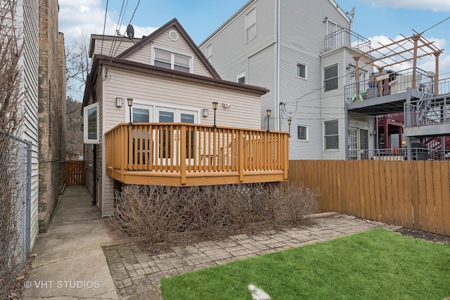 rear view of house with fence and a deck