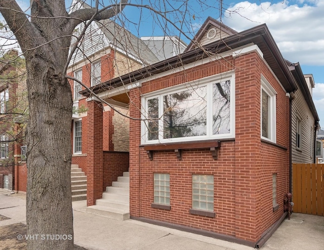 view of side of property featuring brick siding and fence