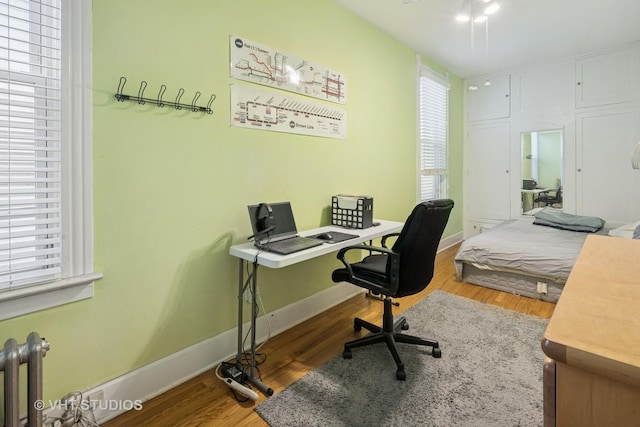 home office with radiator heating unit, baseboards, and wood finished floors