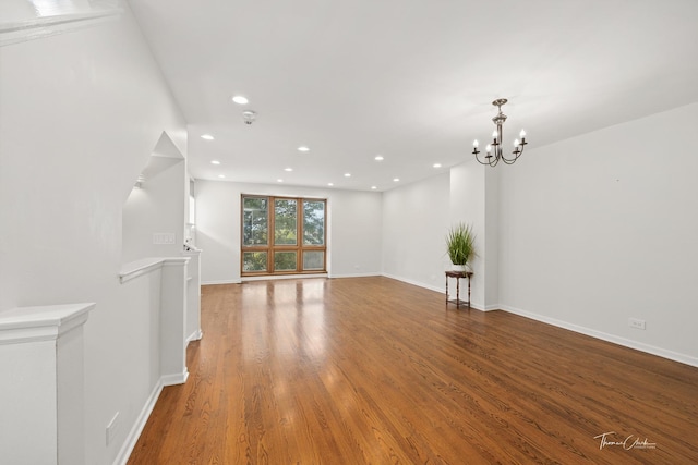 interior space with baseboards, a notable chandelier, wood finished floors, and recessed lighting