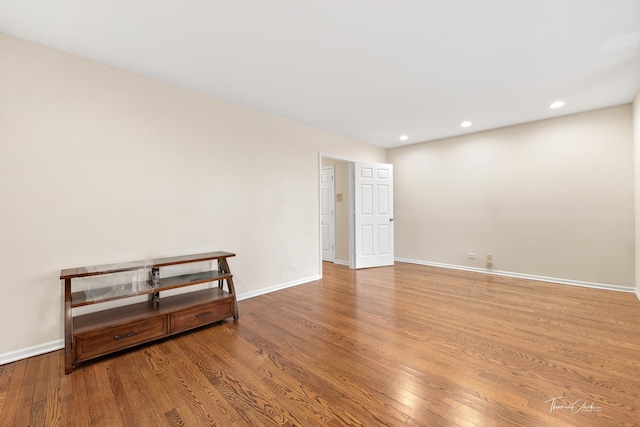 spare room with baseboards, wood finished floors, and recessed lighting