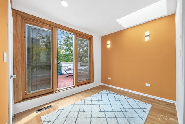 doorway to outside with a skylight, baseboards, visible vents, and wood finished floors