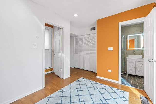 bedroom with a sink, baseboards, visible vents, and wood finished floors