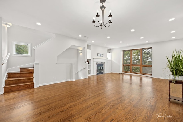 unfurnished living room with stairway, a tiled fireplace, wood finished floors, and recessed lighting