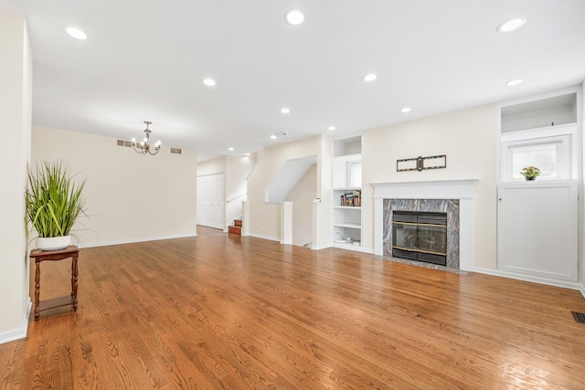 living area featuring built in shelves, recessed lighting, a premium fireplace, wood finished floors, and stairs