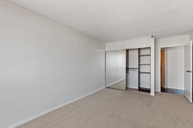 unfurnished bedroom with a closet, carpet flooring, a textured ceiling, and baseboards