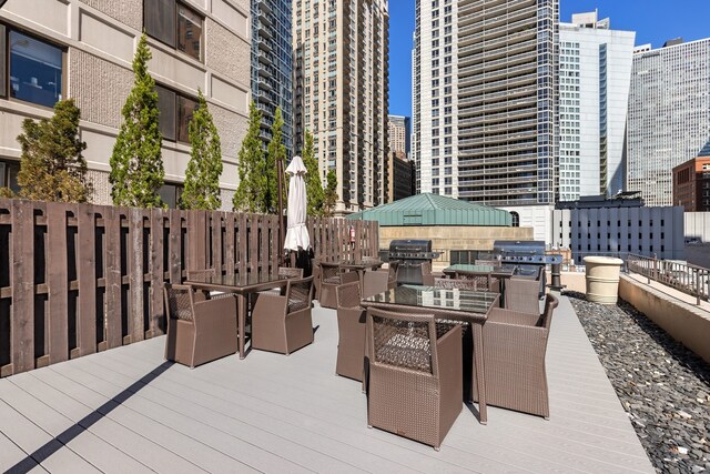 view of patio featuring outdoor dining space, a deck, a view of city, and a grill