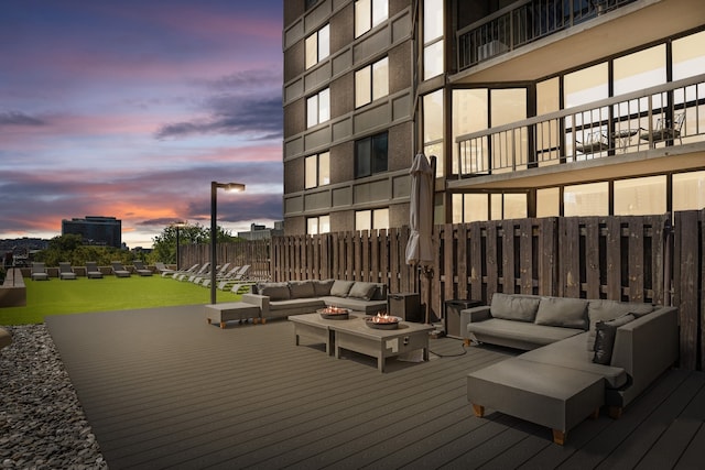 deck at dusk featuring an outdoor living space with a fire pit and fence