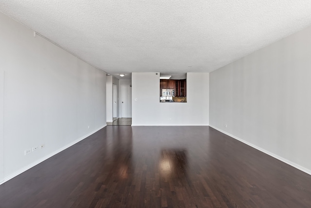 unfurnished living room featuring baseboards, a textured ceiling, and dark wood-style floors