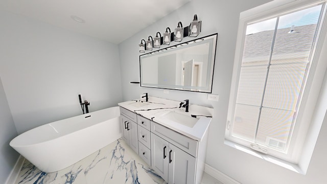 bathroom featuring double vanity, marble finish floor, a freestanding tub, and a sink