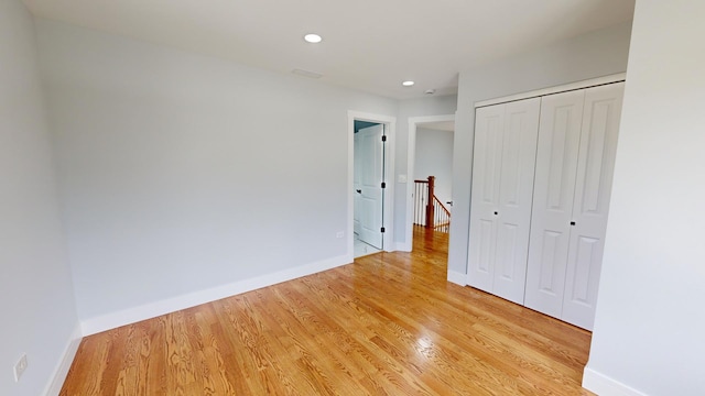 unfurnished bedroom with a closet, light wood-style flooring, and baseboards