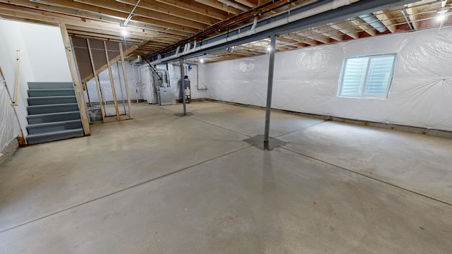 unfinished basement with gas water heater, heating unit, and stairs