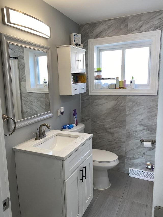 bathroom featuring visible vents, a shower with shower curtain, toilet, vanity, and tile walls