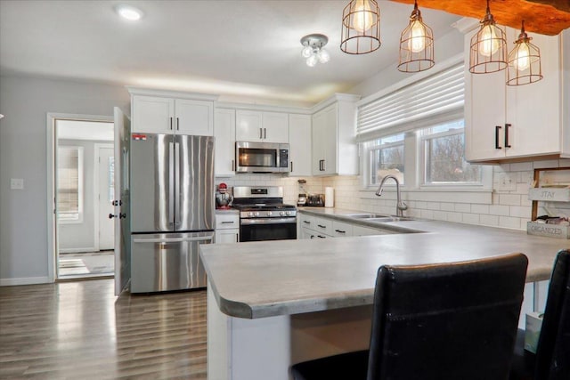 kitchen featuring appliances with stainless steel finishes, white cabinetry, a sink, and tasteful backsplash