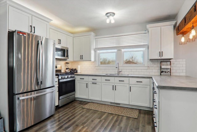 kitchen with appliances with stainless steel finishes, white cabinets, a sink, and dark wood-type flooring