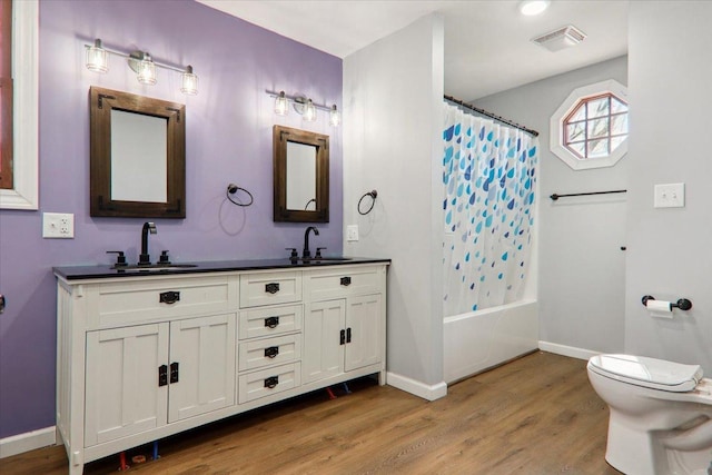 bathroom featuring toilet, wood finished floors, a sink, and visible vents