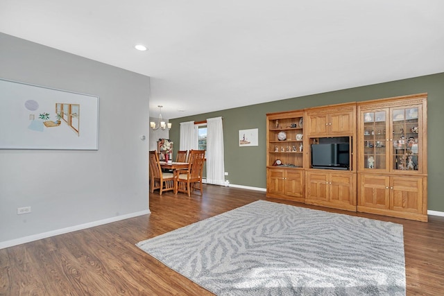 living area featuring dark wood-type flooring, an inviting chandelier, and baseboards