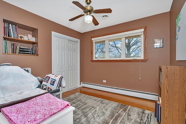 office area featuring ceiling fan, visible vents, baseboard heating, and wood finished floors