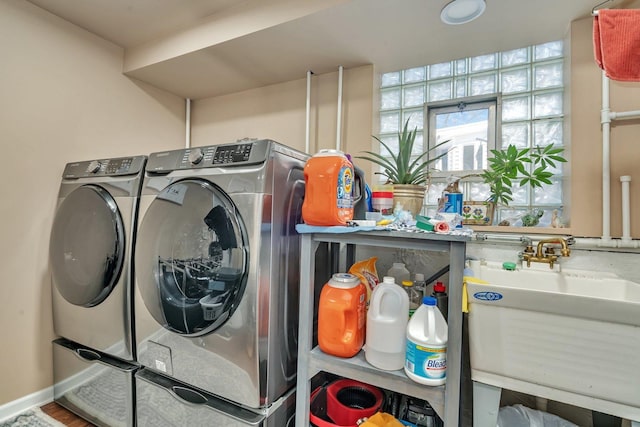 clothes washing area with washer and dryer, laundry area, and a sink