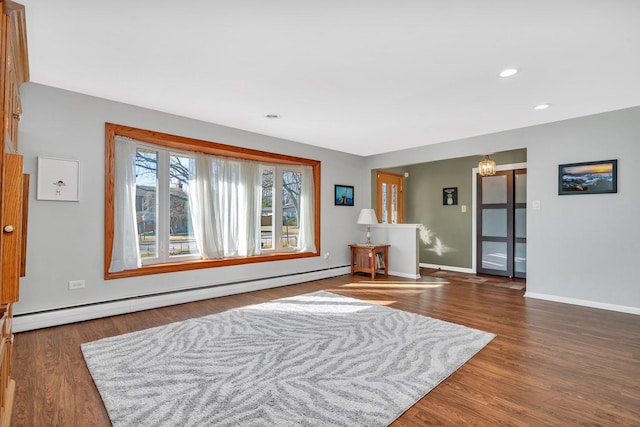 interior space with baseboards, a baseboard heating unit, wood finished floors, and recessed lighting