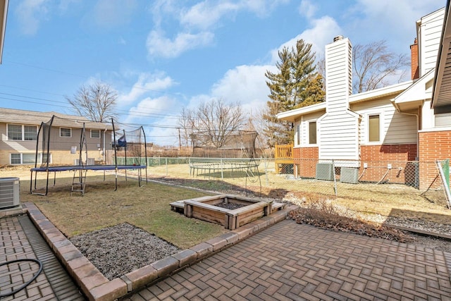 view of yard with a patio, a trampoline, cooling unit, and fence