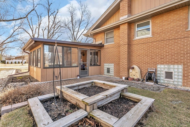 rear view of house featuring a sunroom and brick siding