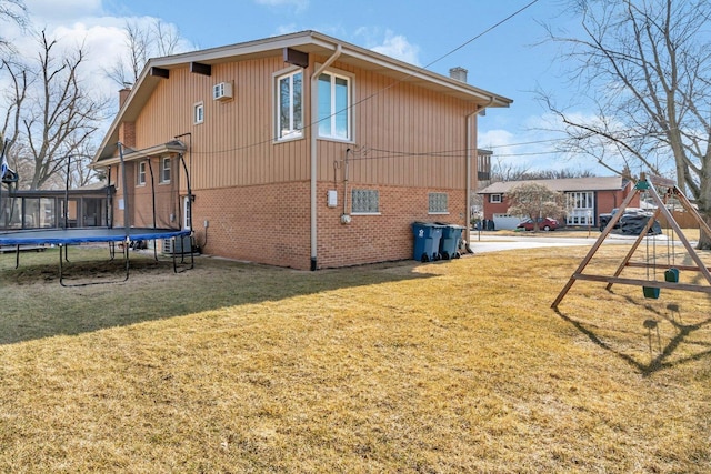 view of home's exterior featuring a lawn, a chimney, a trampoline, a playground, and brick siding