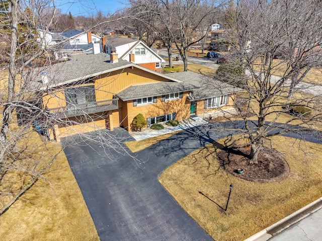 view of front of property with driveway, a balcony, a shingled roof, and a residential view