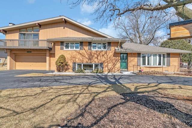 split level home with a garage, aphalt driveway, and brick siding