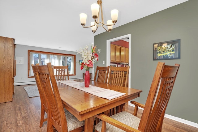 dining space featuring baseboards, baseboard heating, wood finished floors, and a chandelier