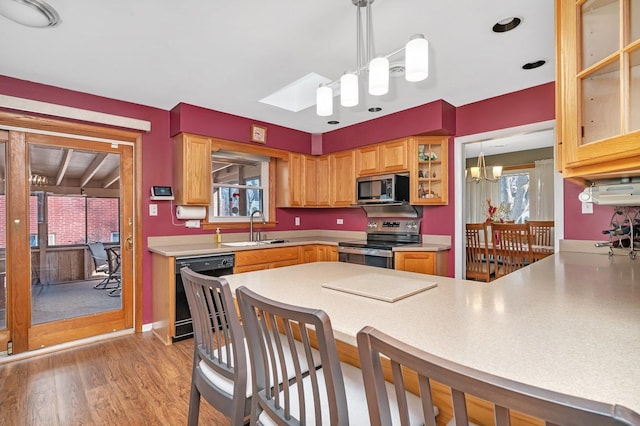 kitchen with appliances with stainless steel finishes, light countertops, a kitchen bar, a chandelier, and a sink