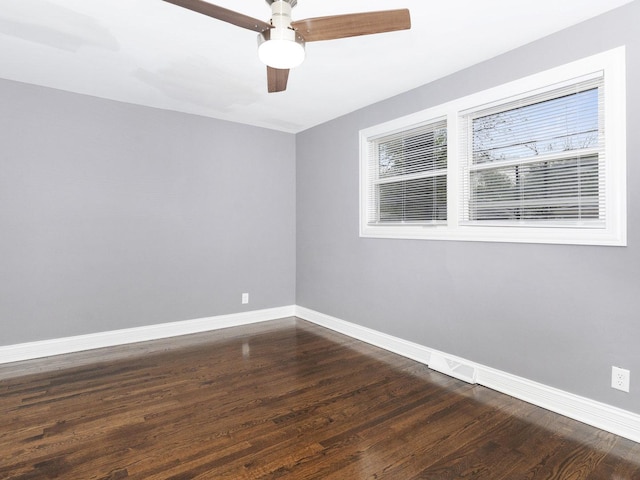 empty room featuring ceiling fan, dark wood finished floors, and baseboards