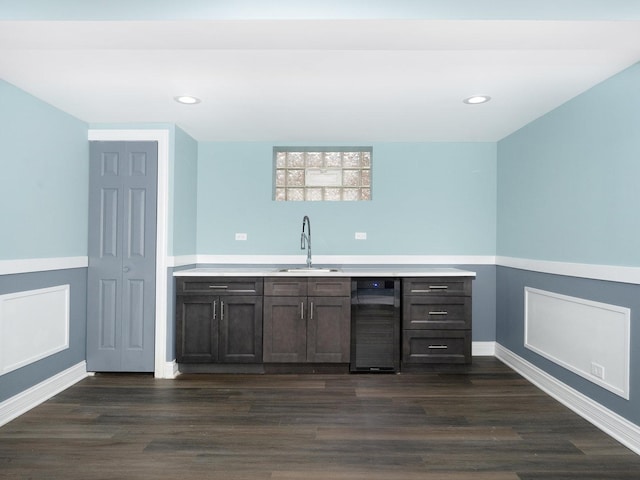 bar with dark wood finished floors, beverage cooler, a sink, and recessed lighting