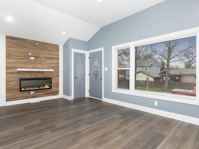 unfurnished living room with a large fireplace, wood finished floors, lofted ceiling, and baseboards