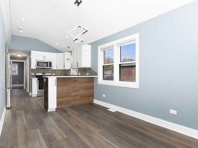 kitchen featuring tasteful backsplash, a peninsula, stainless steel appliances, white cabinetry, and a sink