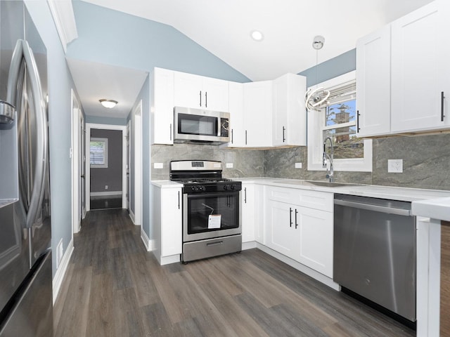 kitchen with lofted ceiling, appliances with stainless steel finishes, light countertops, and a sink