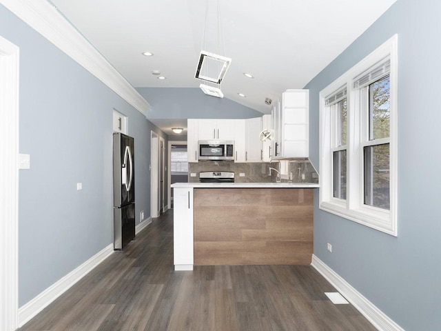 kitchen featuring appliances with stainless steel finishes, a wealth of natural light, a peninsula, and tasteful backsplash