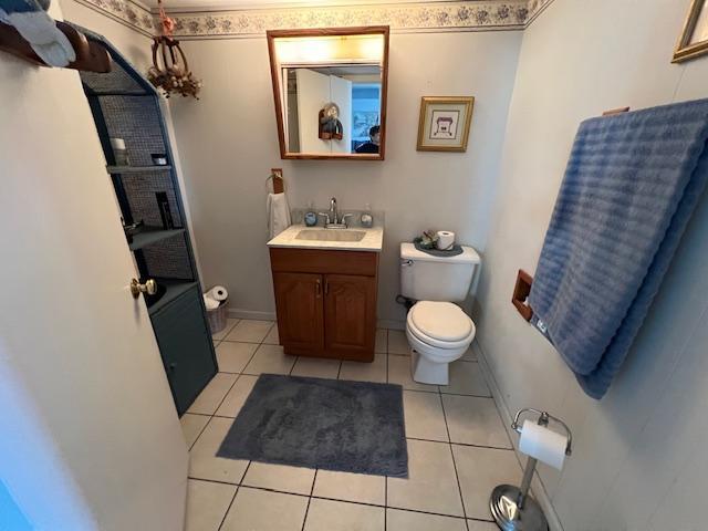 bathroom featuring baseboards, vanity, toilet, and tile patterned floors