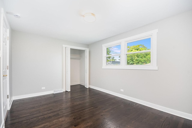 unfurnished bedroom featuring a closet, baseboards, and dark wood-style flooring