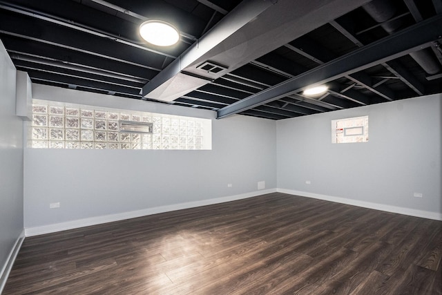 basement with dark wood-style floors, visible vents, and baseboards