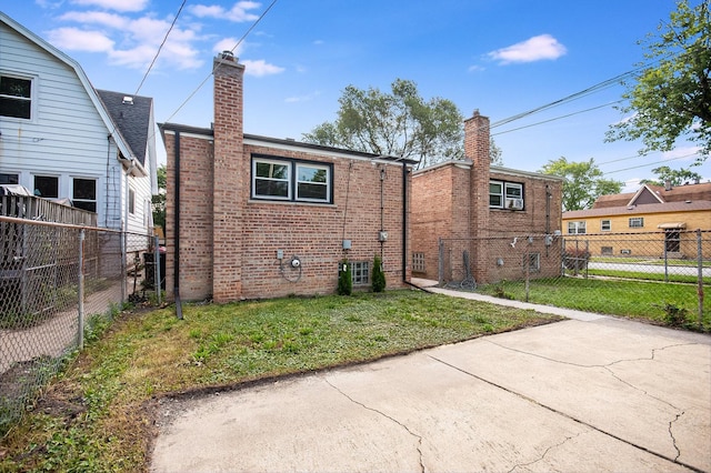 back of house with brick siding, a yard, a chimney, and a fenced backyard